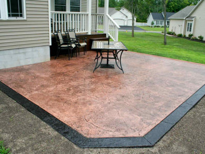 Stamped and stained back yard patio with black stained concrete edge and rustic red concrete inside.