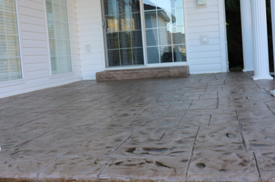 Stamped concrete patio outside of Lansing, Michigan with a sliding door and concrete step.