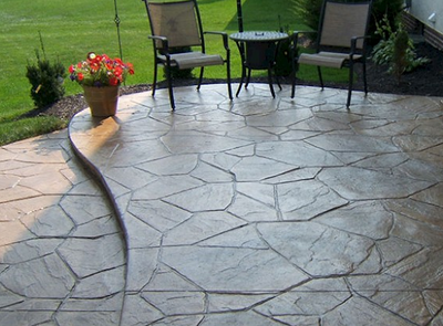 Stamped patio and patio chairs with a flower pot at a home in Lansing.
