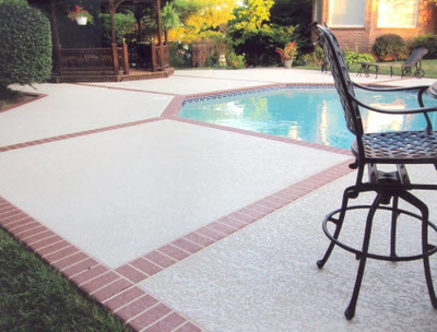 Pool surround with white concrete in middle and surrounded with red stamped concrete in a brick pattern.
