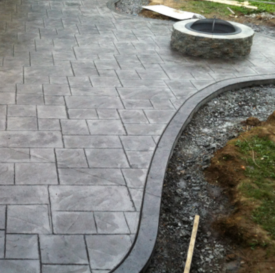 Gray stamped patio with built in concrete brick fire pit.